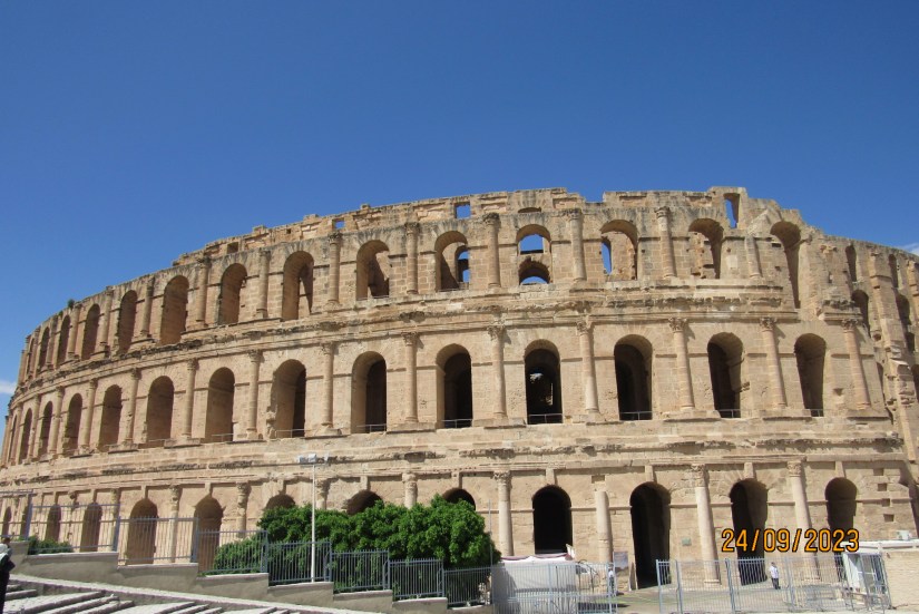 Vista del Anfiteatro romano en El Djem, Túnez, mostrando su estructura elíptica y arcos, bajo un cielo azul claro.